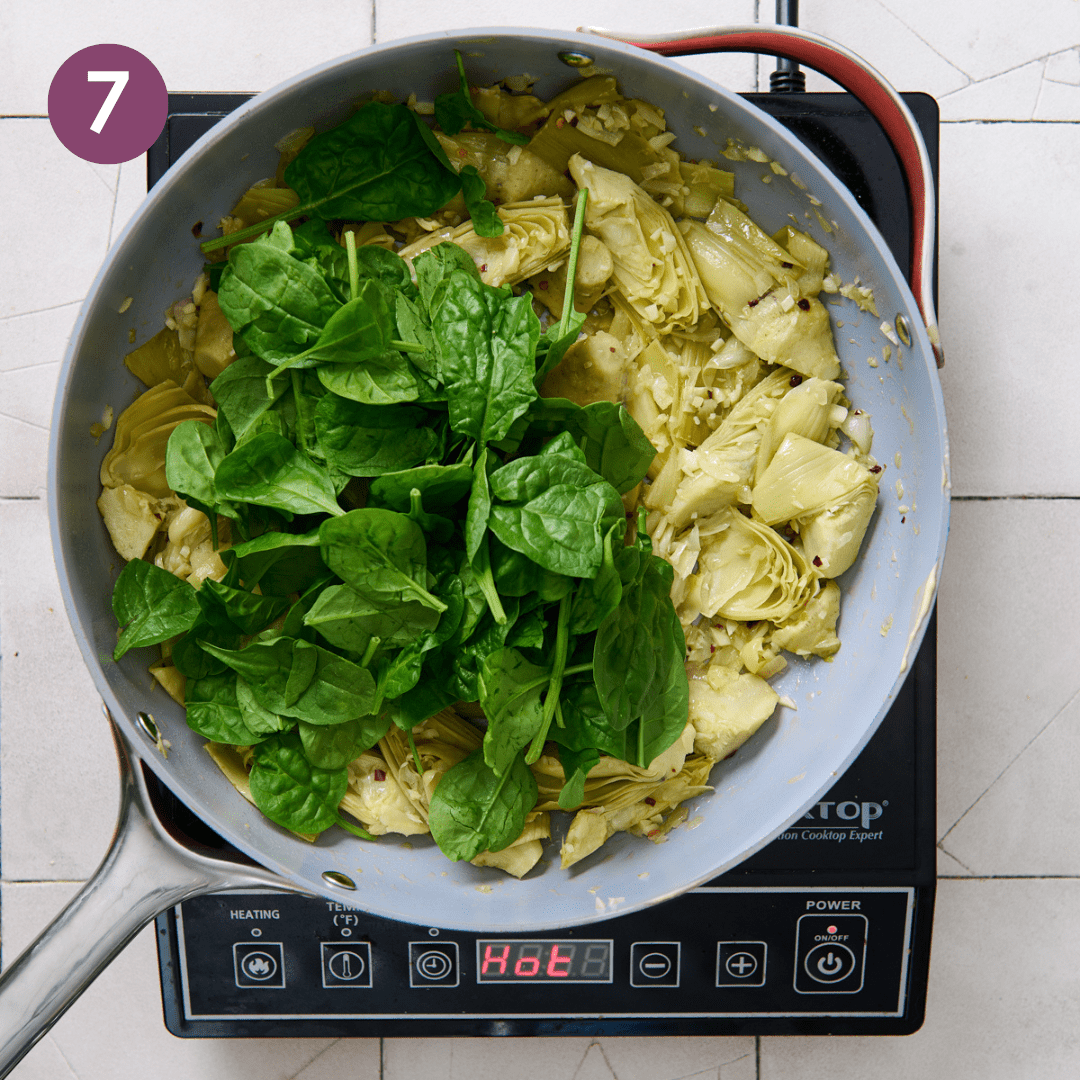Spinach added to artichoke mixture in pan.