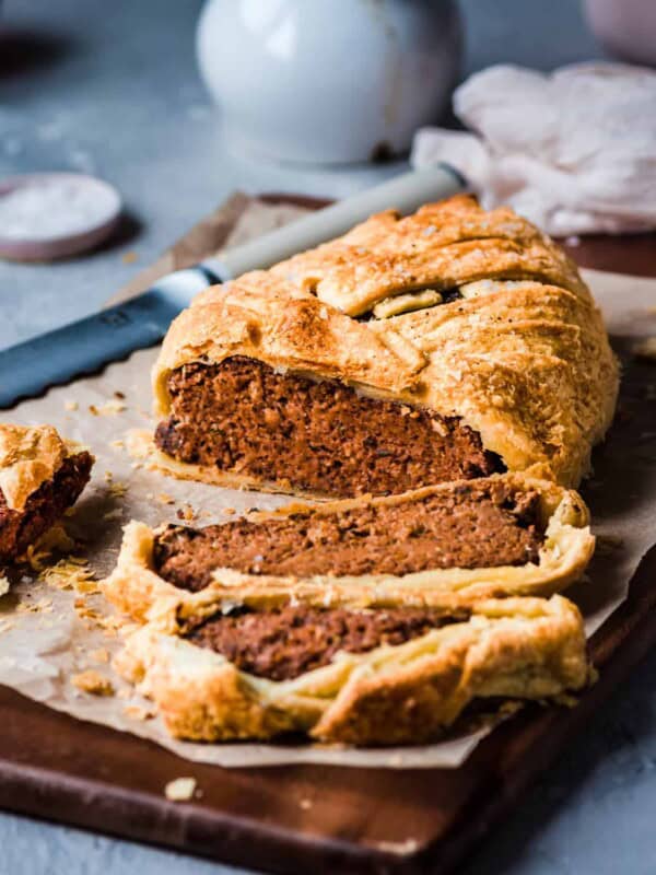 vegan mushroom wellington cut into slices on a parchment paper lined cutting board on a gray table.