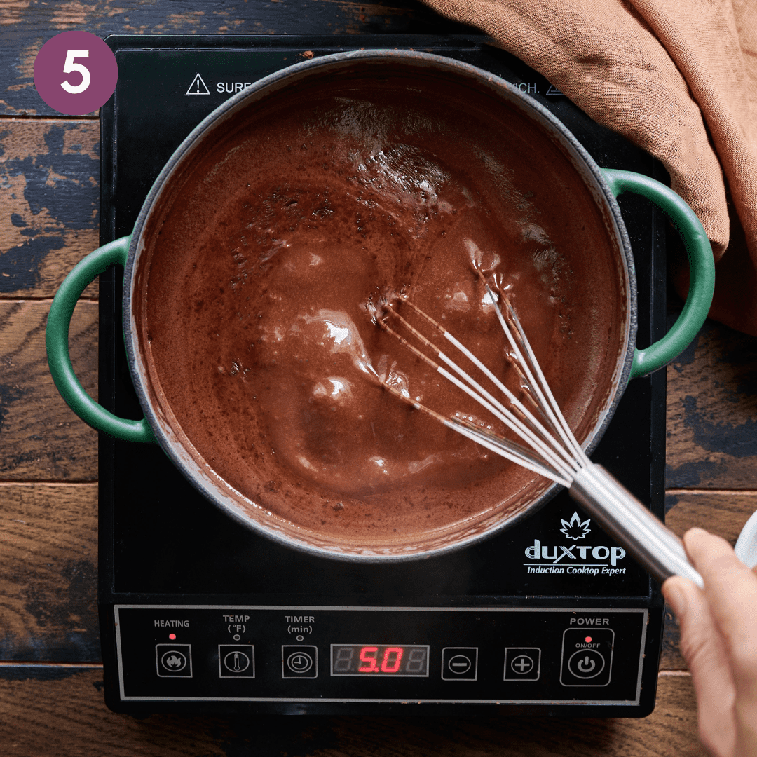 Person whisking hot chocolate mixture.