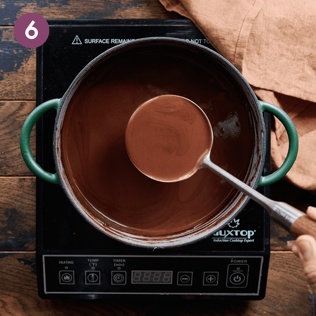 Person ladeling hot chocolate out of the pot.
