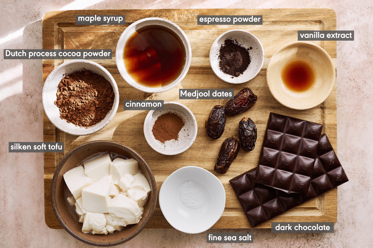 Vegan Chocolate mousse ingredients in various small bowls on a wooden cutting board.