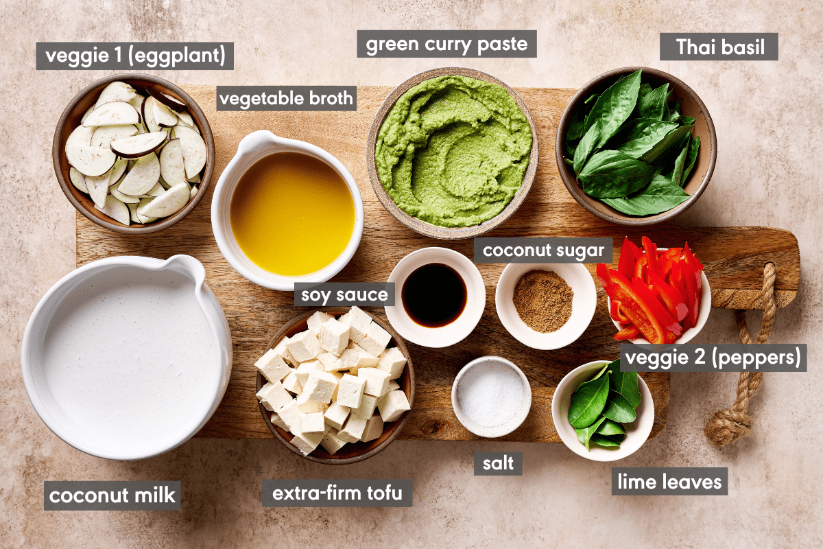 ingredients for vegan Thai green curry on a wooden cutting board with ingredients labeled.