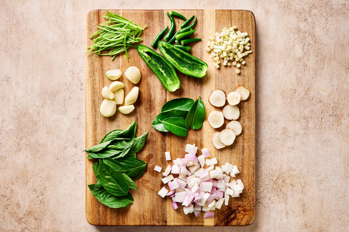 Thai aromatics and herbs laid out on a wooden cutting board.