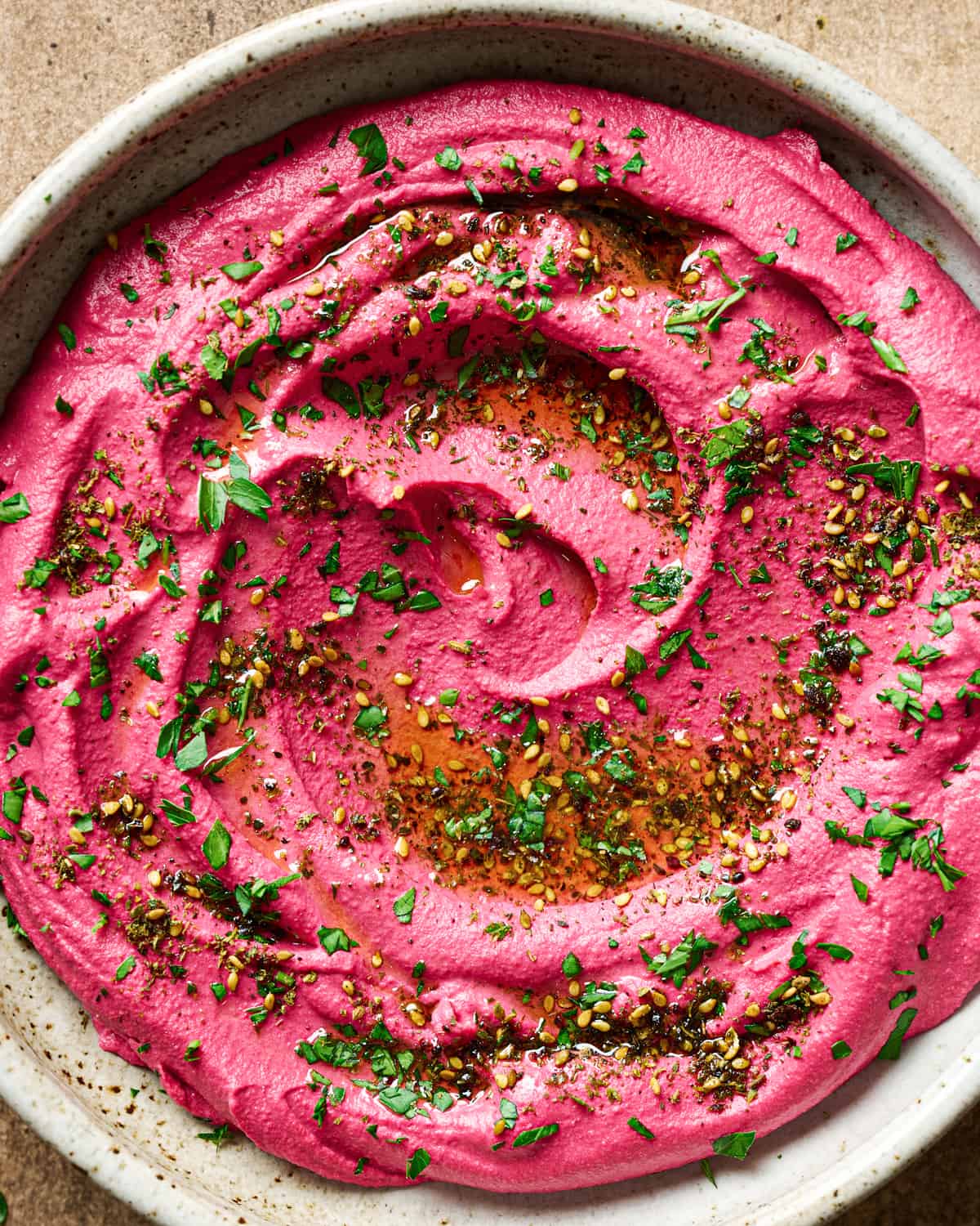 Close up of large shallow bowl of beet hummus on a table.