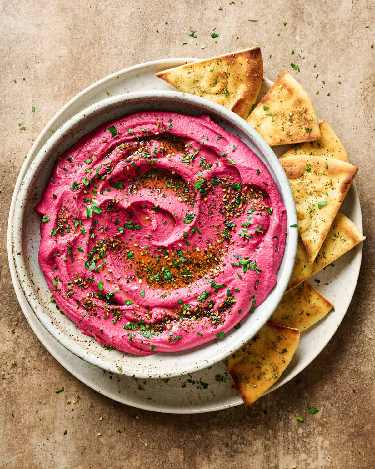 Bowl of beet hummus on a plate with pita bread.