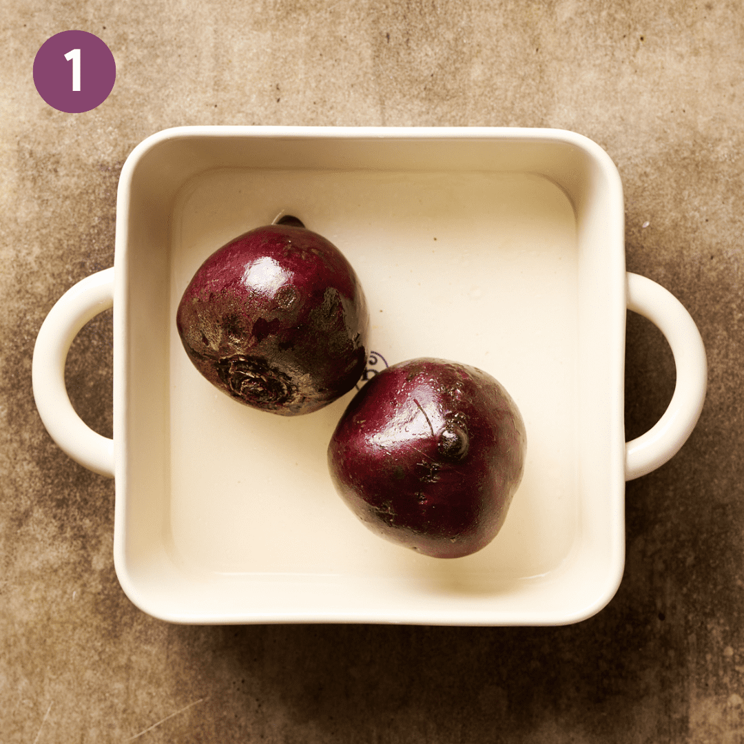 Oiled beets in a baking dish with water.