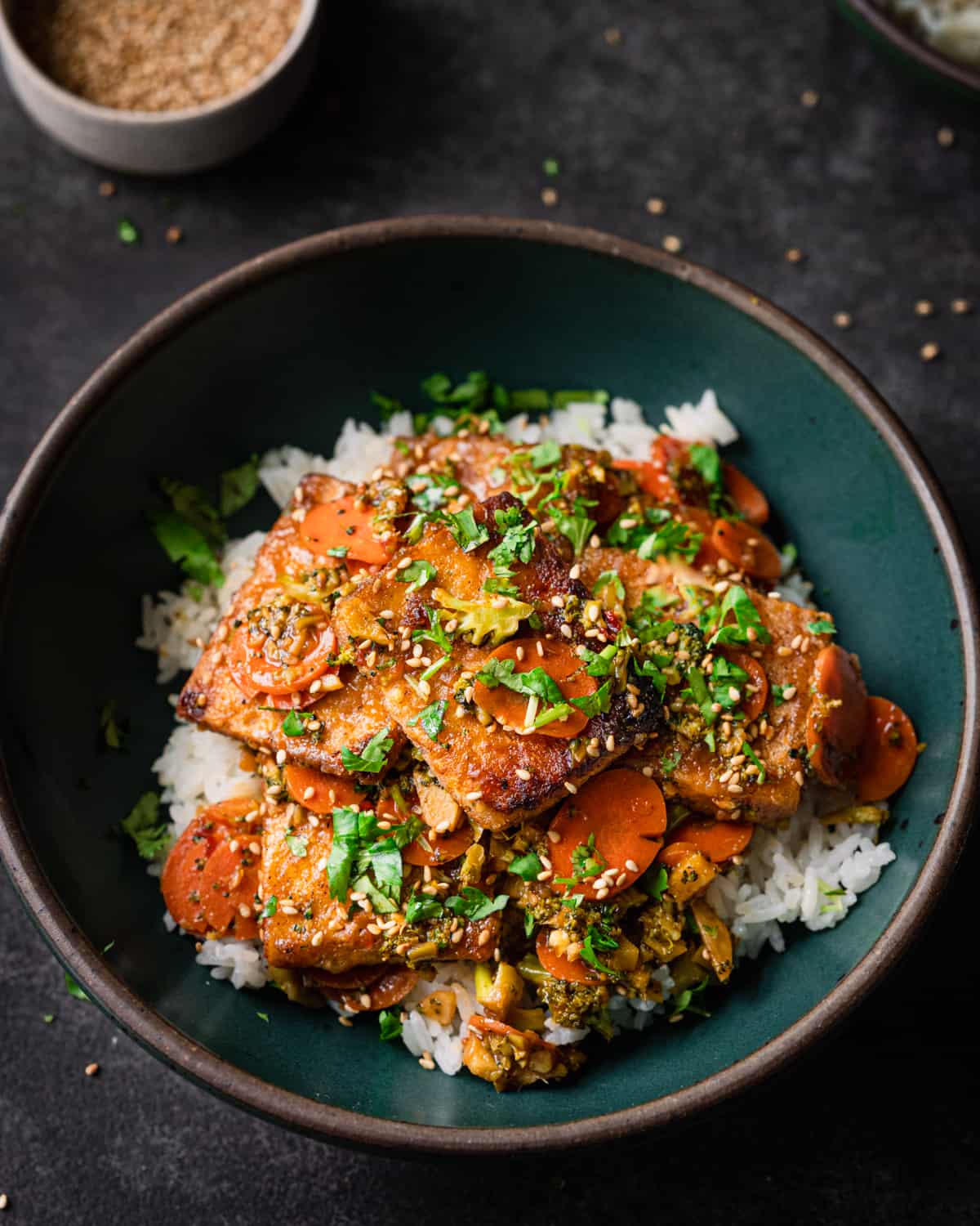 Tofu stir fry with carrots on a bed of rice in blue bowl.