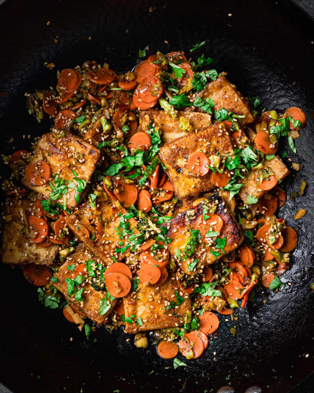 Stir fried tofu with carrots in a wok.