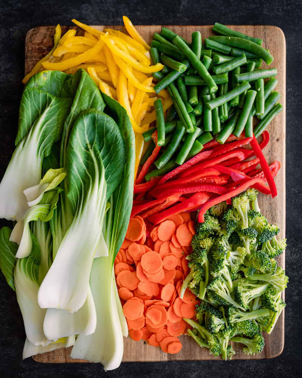 Various chopped vegetables on a large wooden cutting board.