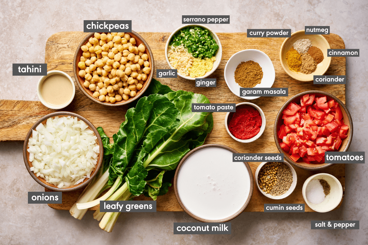 ingredients for vegan Indian chickpea curry laid out on a wooden cutting board with ingredients labeled.