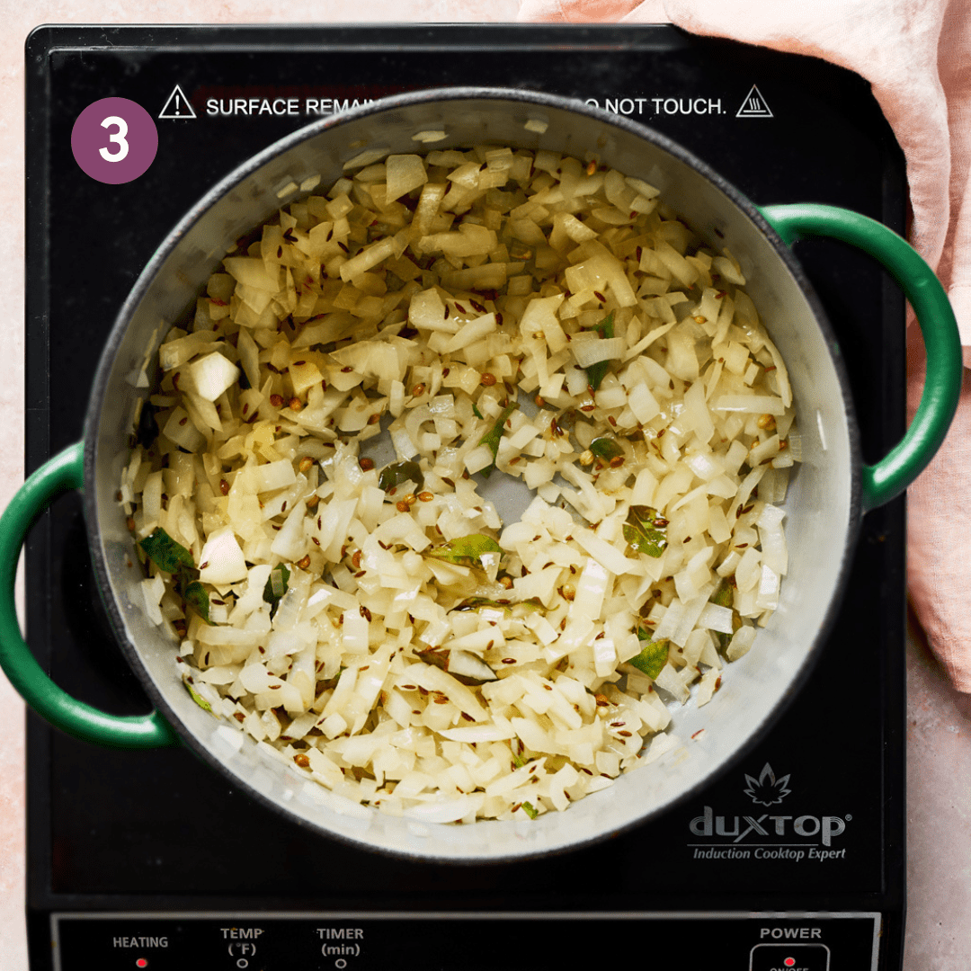 diced onions sauteing with Indian spices in a green dutch oven.