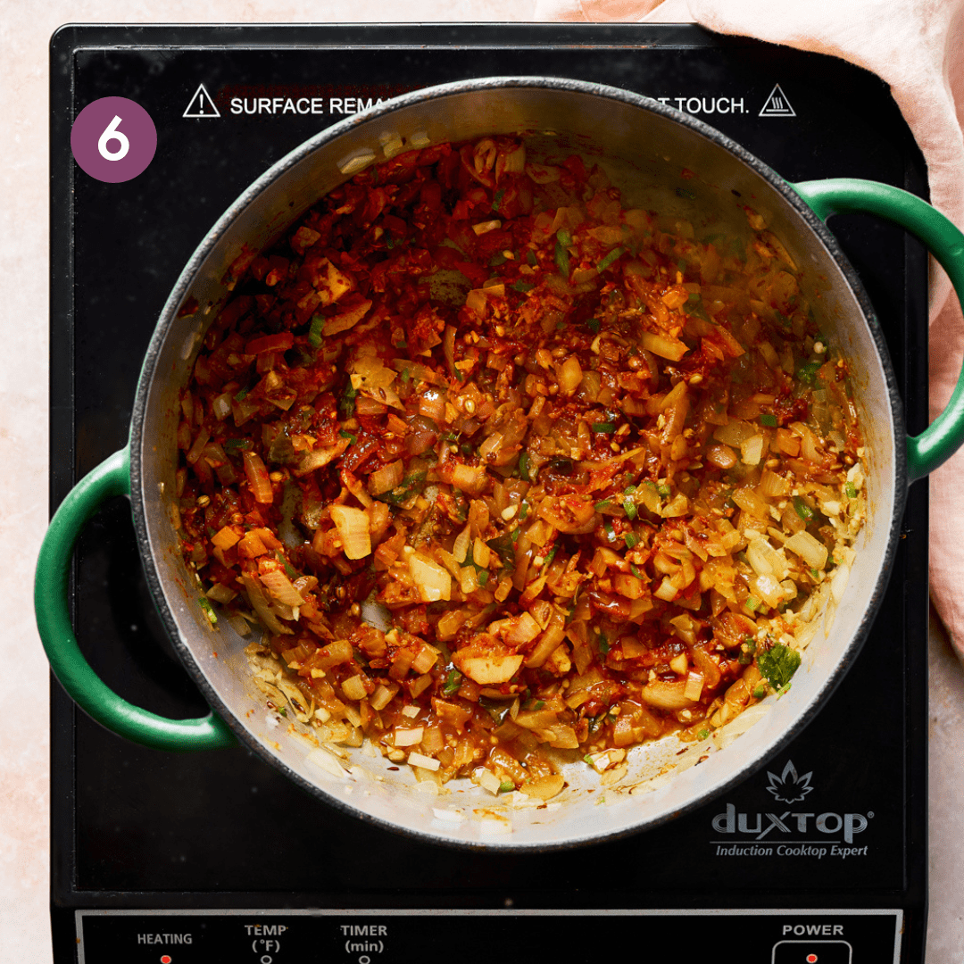 Indian spices and tomato paste stirred into sauteed onions in a Dutch oven.