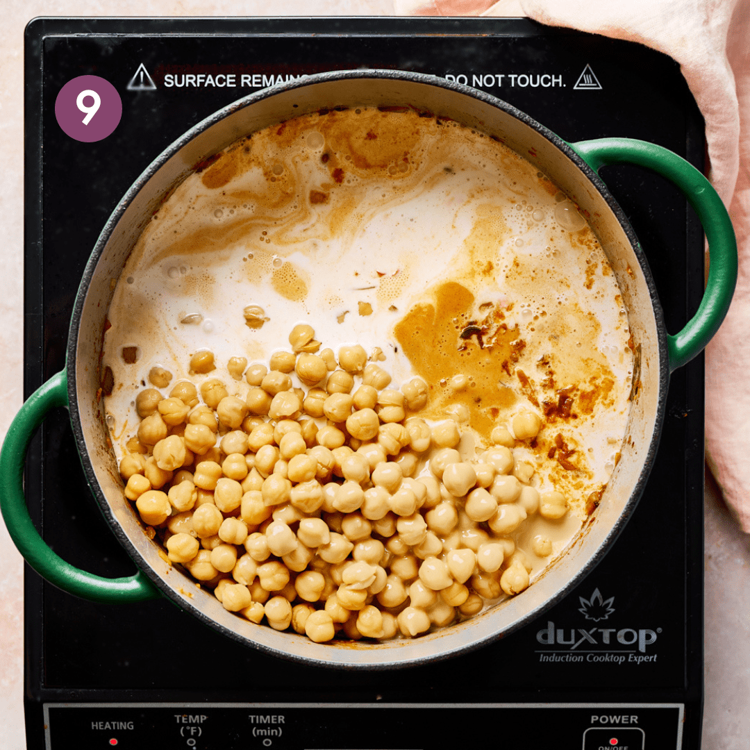 chickpeas, coconut milk, and spices for an Indian chickpea curry in a green dutch oven.