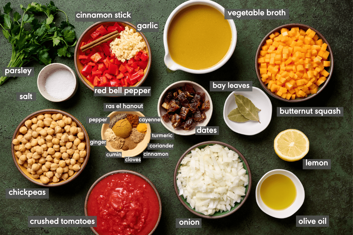ingredients for vegan tagine with chickpeas in individual bowls on a green surface with ingredients labeled.