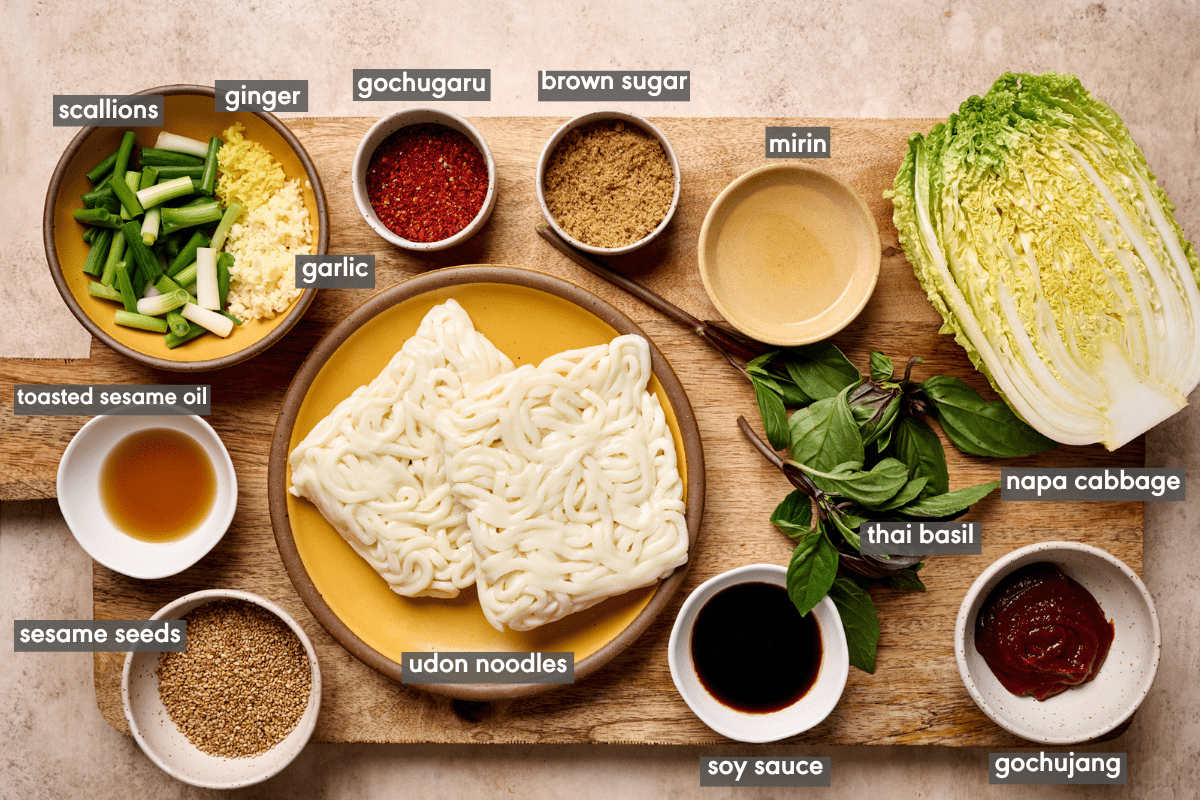 Gochujang noodle ingredients in various bowls and plates on a wooden cutting board.