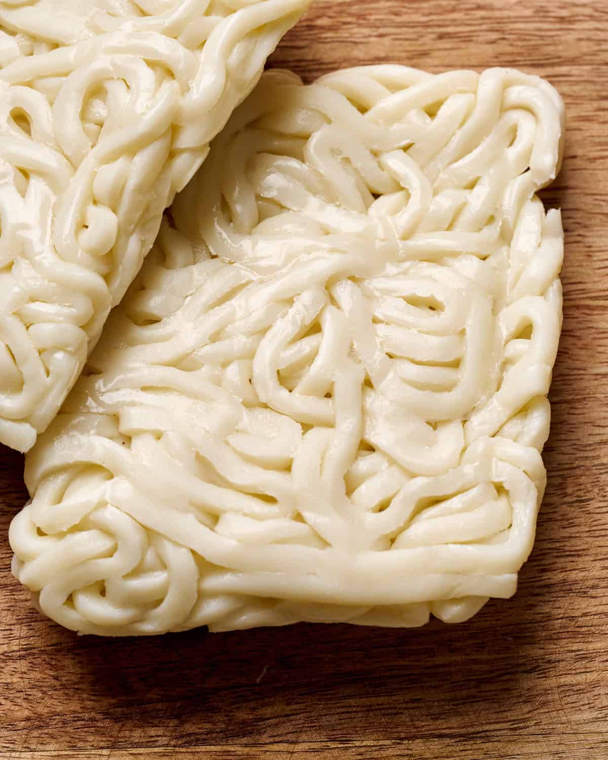 Close up photo of two squares of fresh udon noodles.