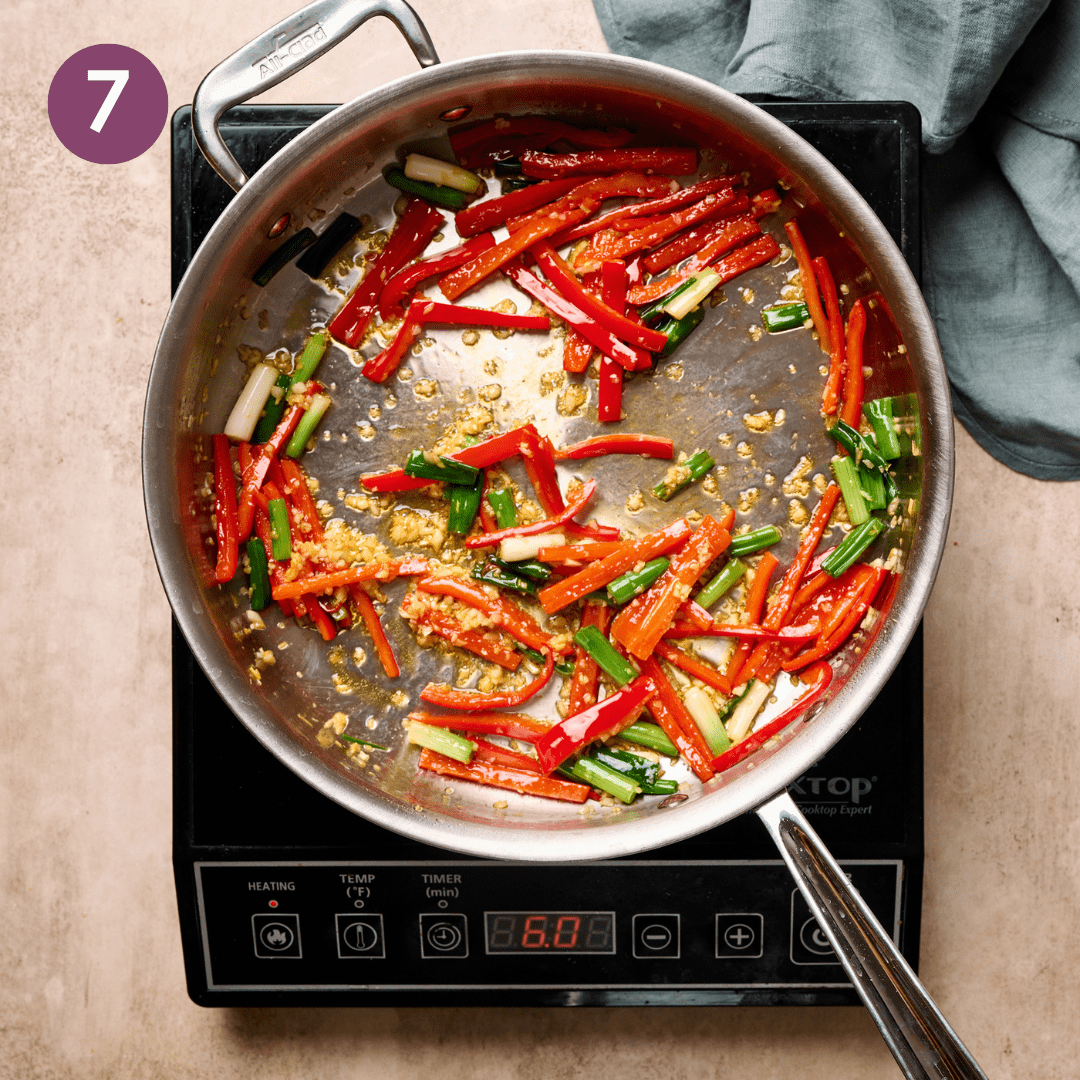 scallion whites and greens, garlic, ginger, and vegetables sauteing in a skillet.