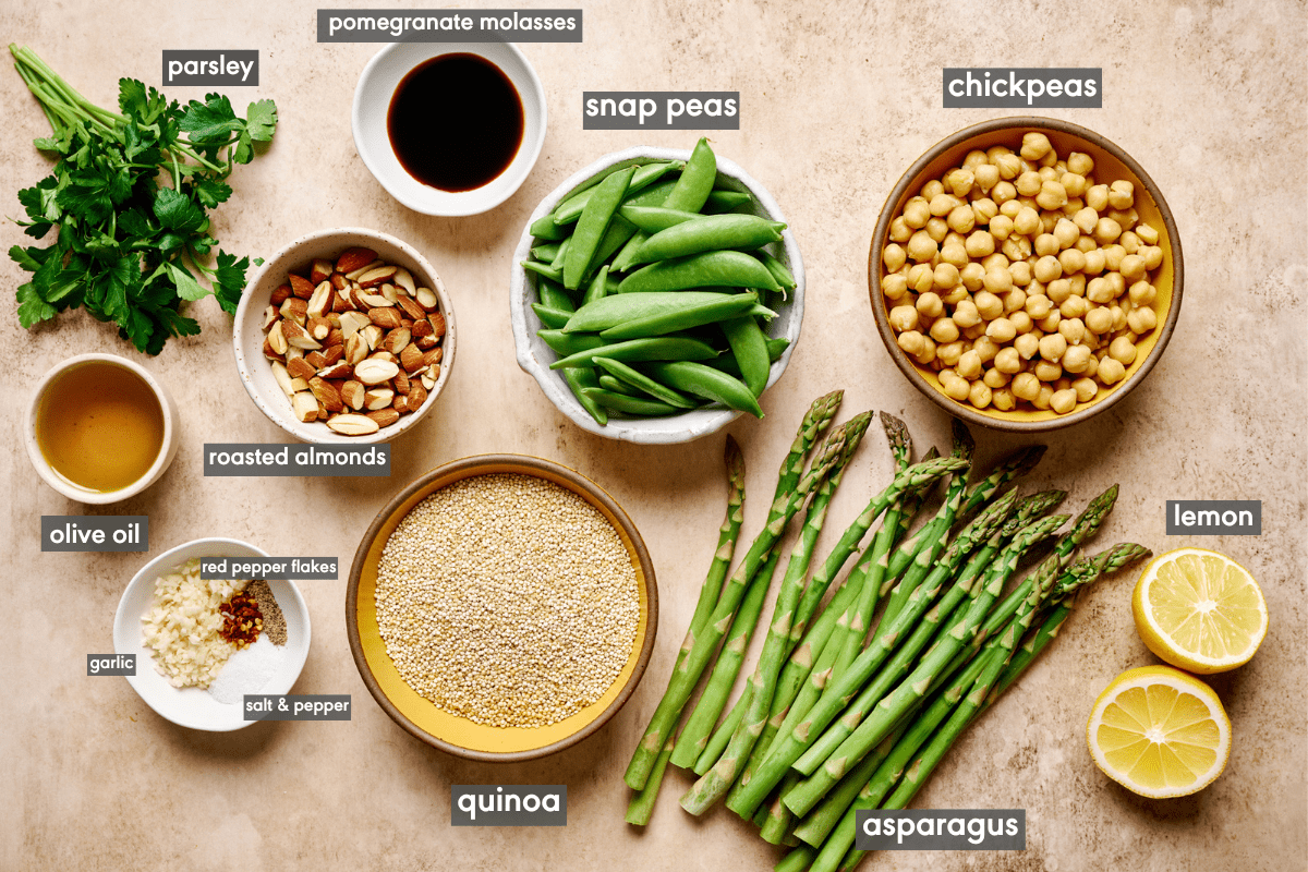 Quinoa salad ingredients laid out in bowls on a cream table.