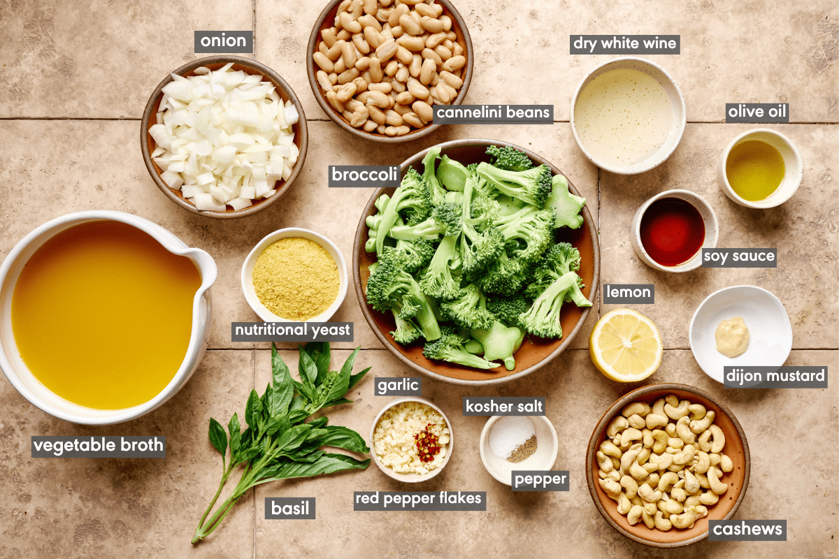 Broccoli soup ingredients in various bowls on a cream colored tile table.