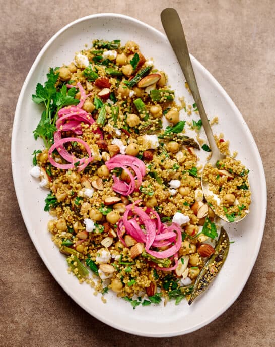 Large oval white plate with quinoa salad, pickled onion and vegan feta.