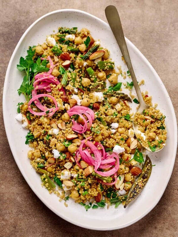 Large oval white plate with quinoa salad, pickled onion and vegan feta.