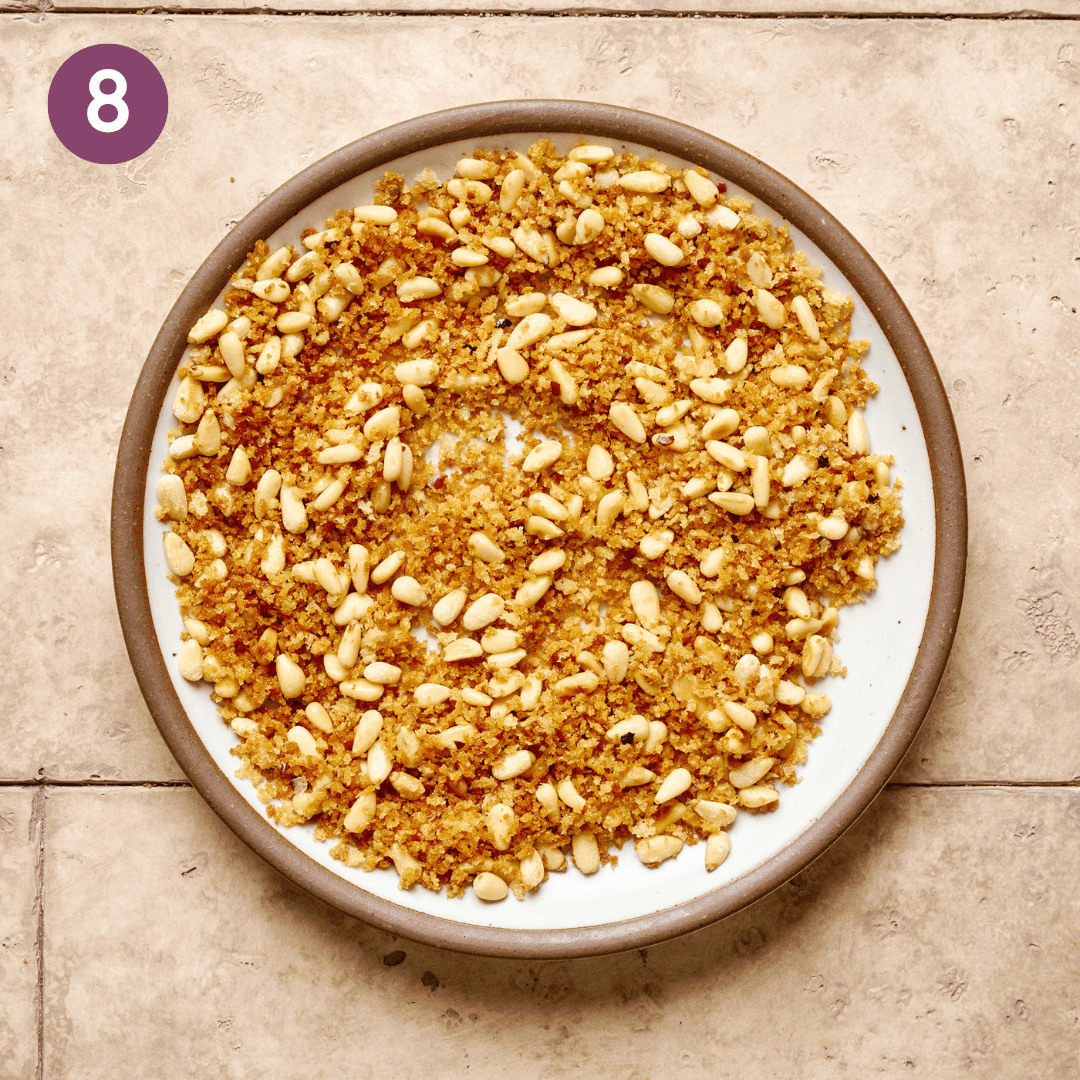 Golden crispy panko and pine nuts on a white plate on a table.