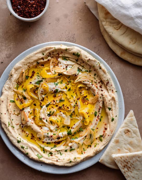 plate of the best hummus with olive oil and herbs with pita bread.