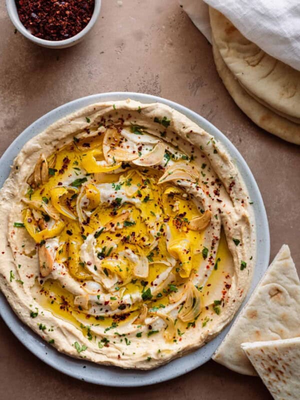 plate of the best hummus with olive oil and herbs with pita bread.