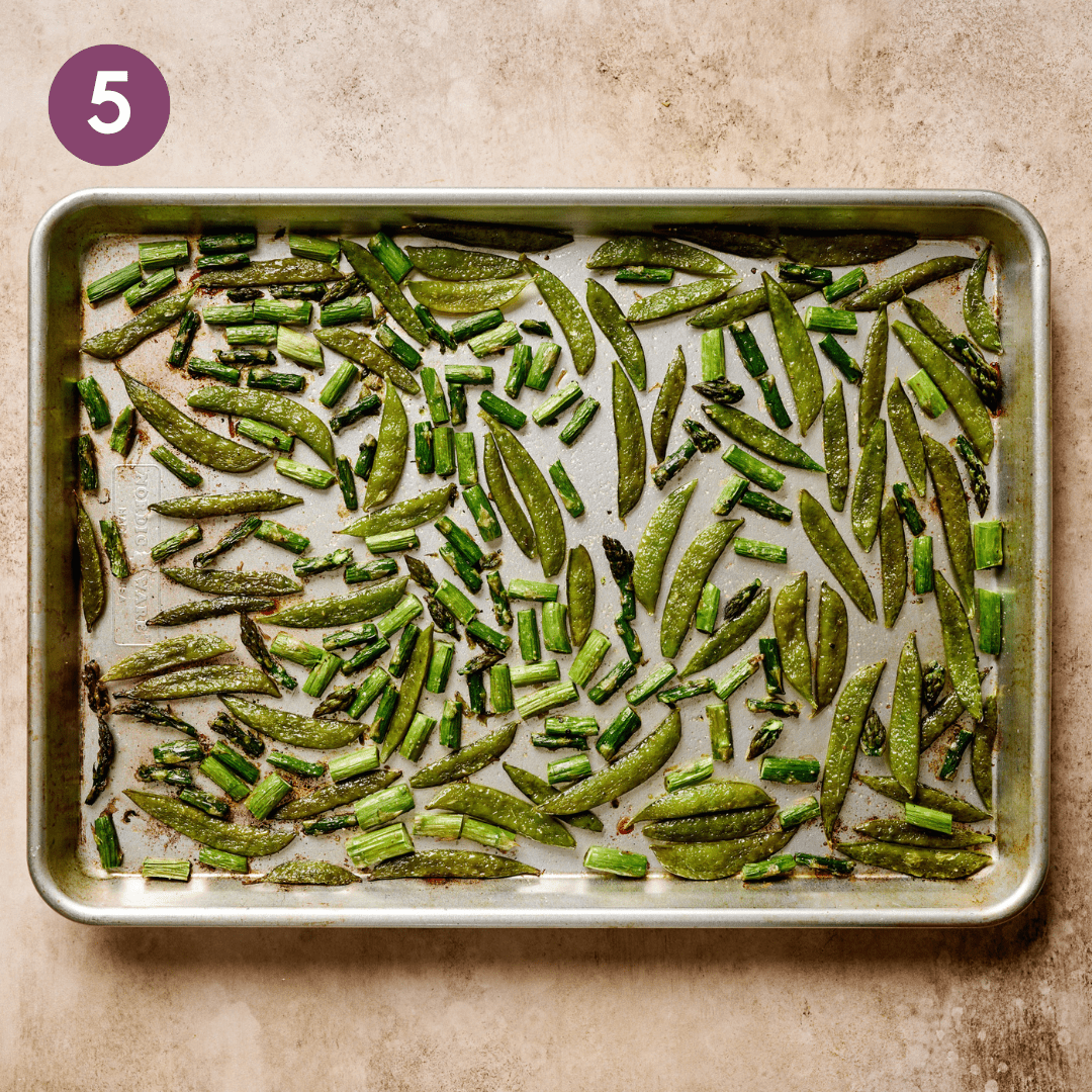 Roasted asparagus and snap peas on a baking sheet.