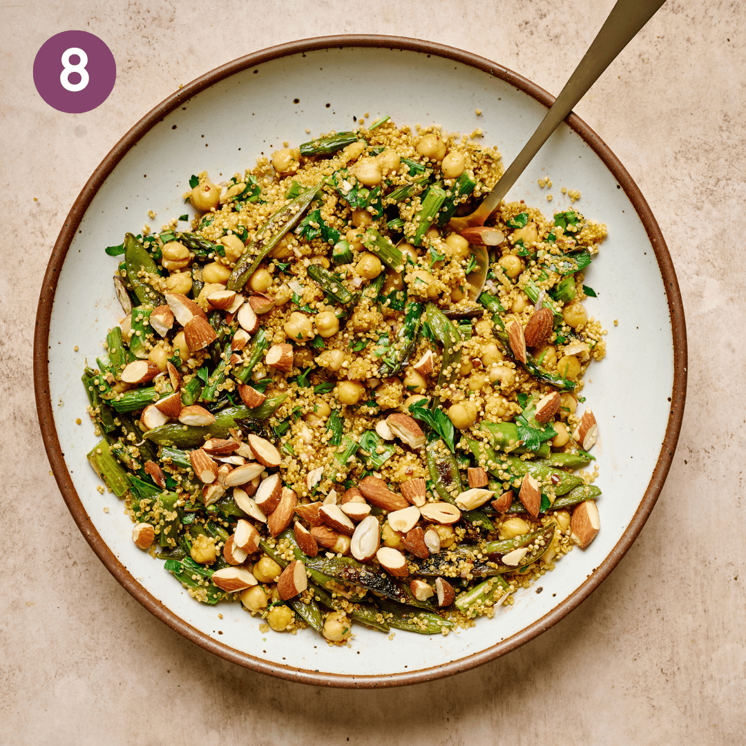 A plate of finished quinoa salad with veggies mixed in topped with roasted almonds.