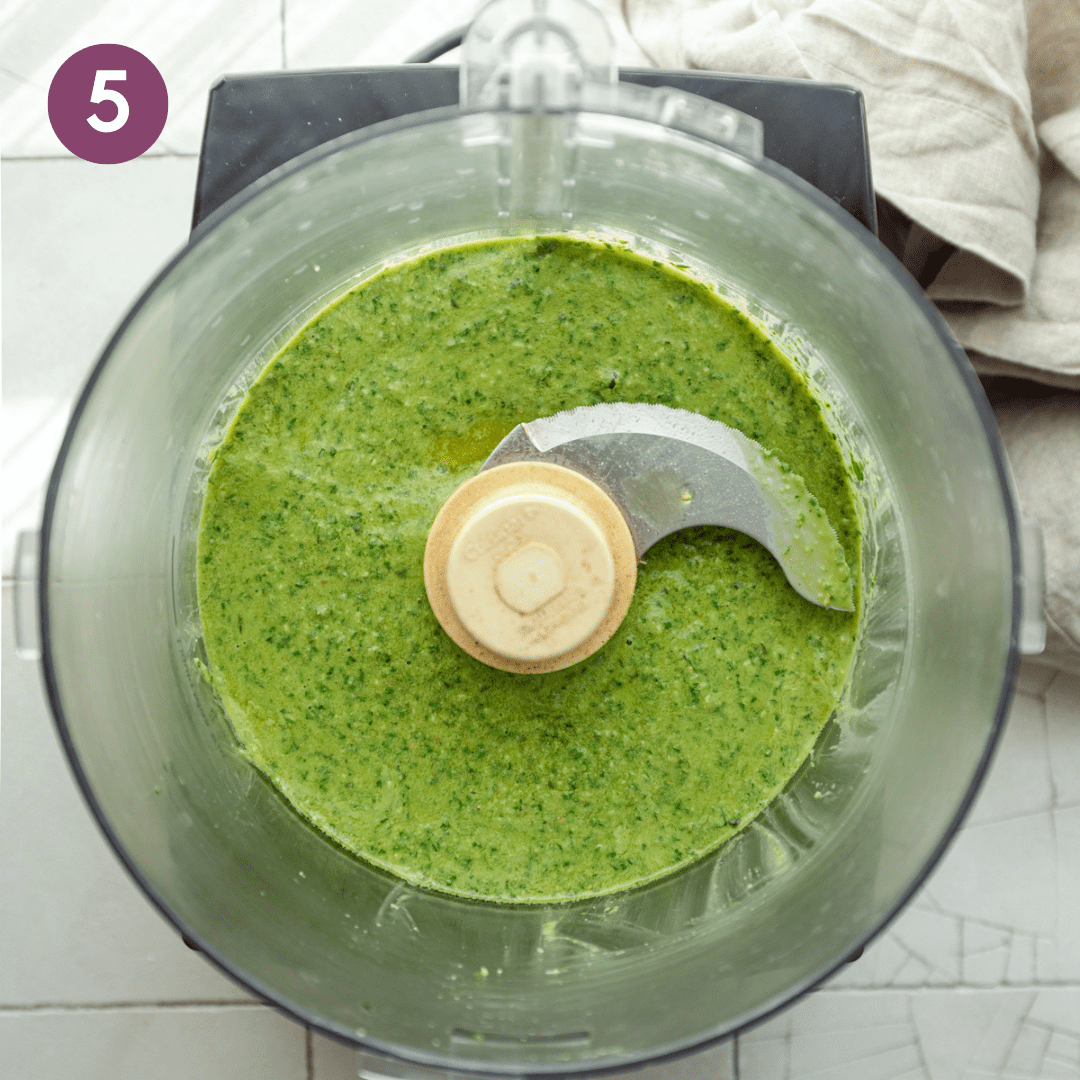 Pasty textured pesto in the food processor after olive oil is added.