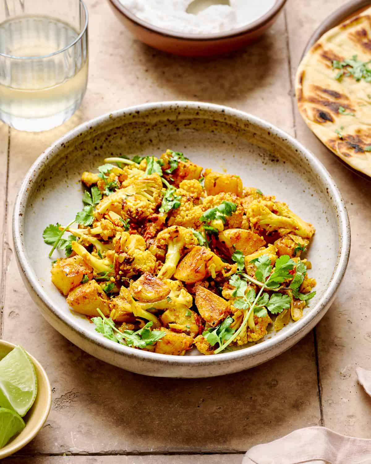 Aloo Gobi in a white bowl  on a brown tile table.