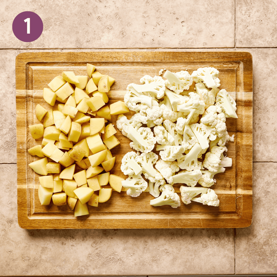 Chopped potatoes and cauliflower on a cutting board.