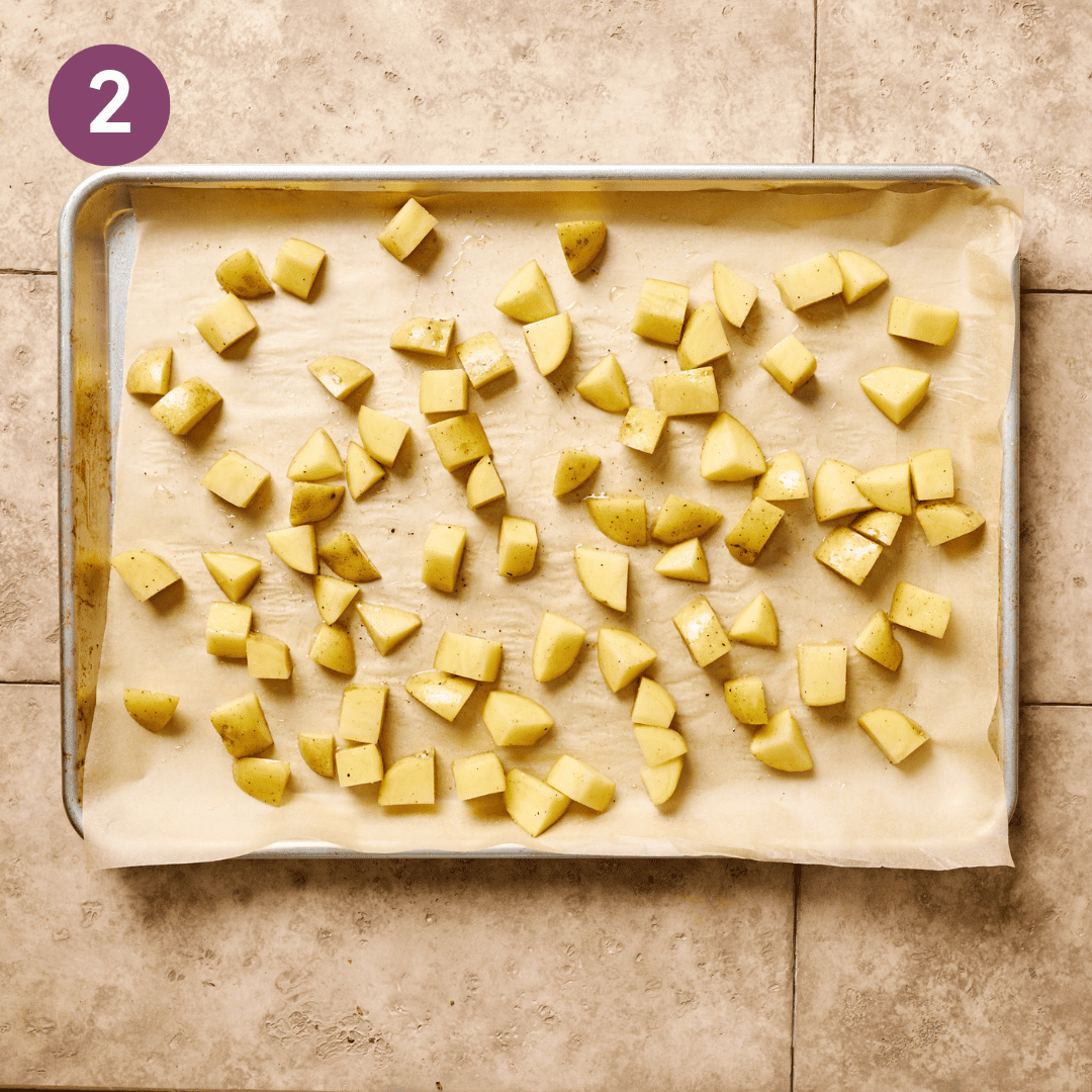 Diced potatoes on a parchment paper lined baking sheet.