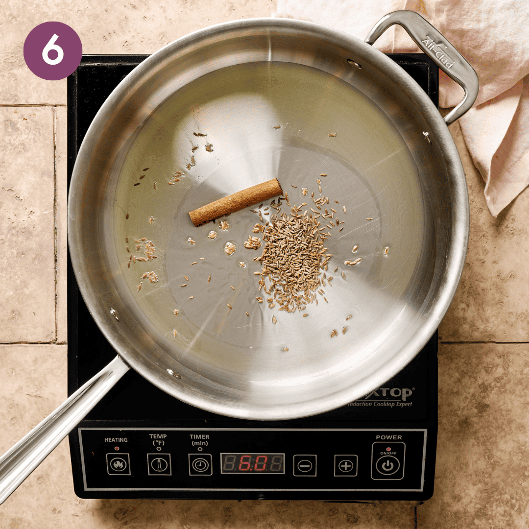 Oil, cumin seeds and cinnamon stick in a deep saute pan.