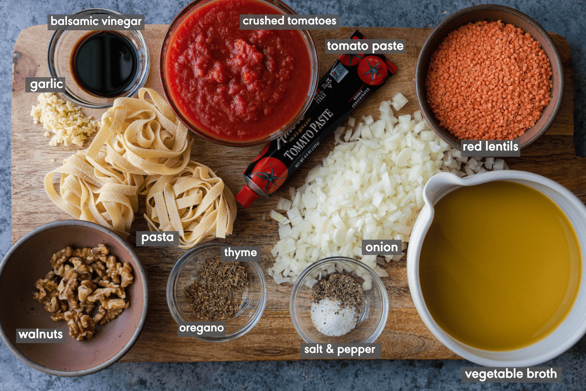 Vegan bolognese ingredients in various small bowls on a wooden cutting board.