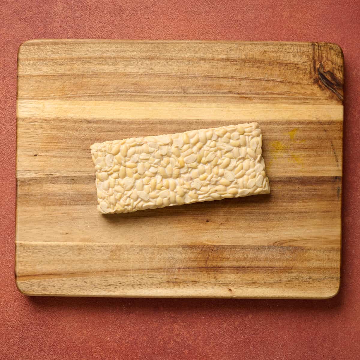 Block of tempeh on a wooden cutting board.