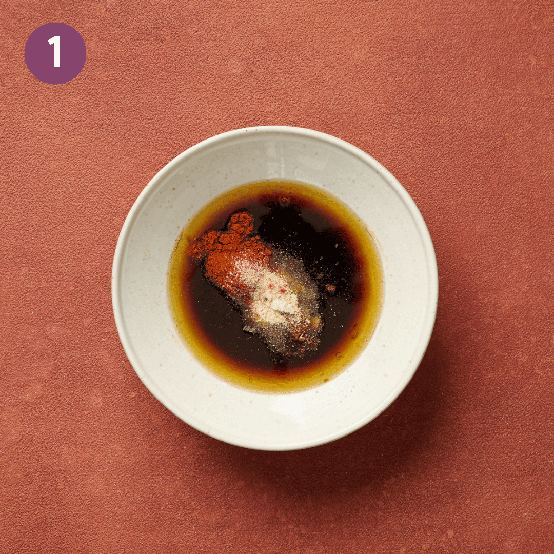 Marinade ingredients in a white bowl on a red table.