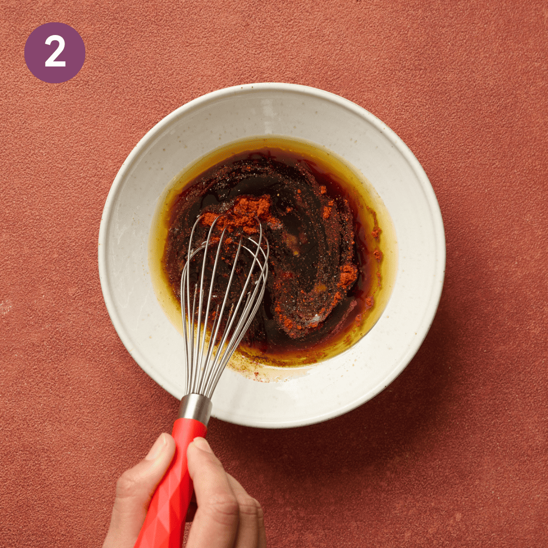 Person whisking marinade ingredients together in a bowl.