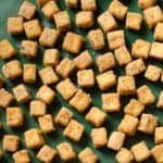 crispy baked tofu cubes on a green sheet pan.