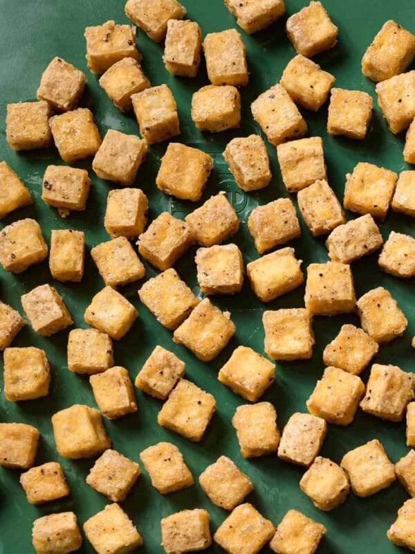 crispy baked tofu cubes on a green sheet pan.