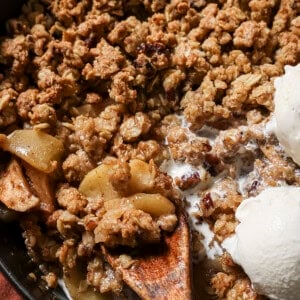 Apple crisp, vegan vanilla ice cream and a spoon in a cast-iron pan.