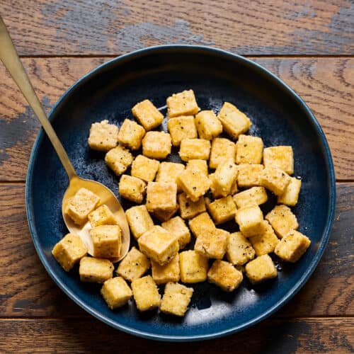 Fried tofu in a bowl on a wooden table.