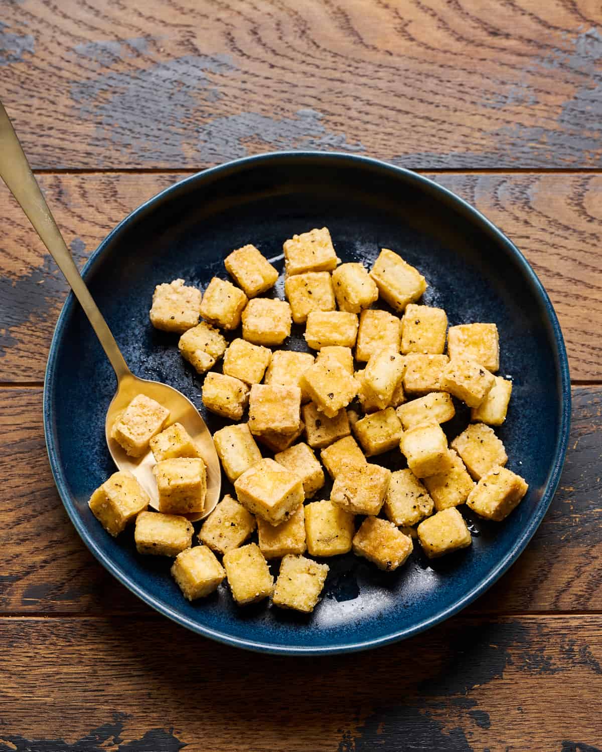Fried tofu in a bowl on a wooden table.