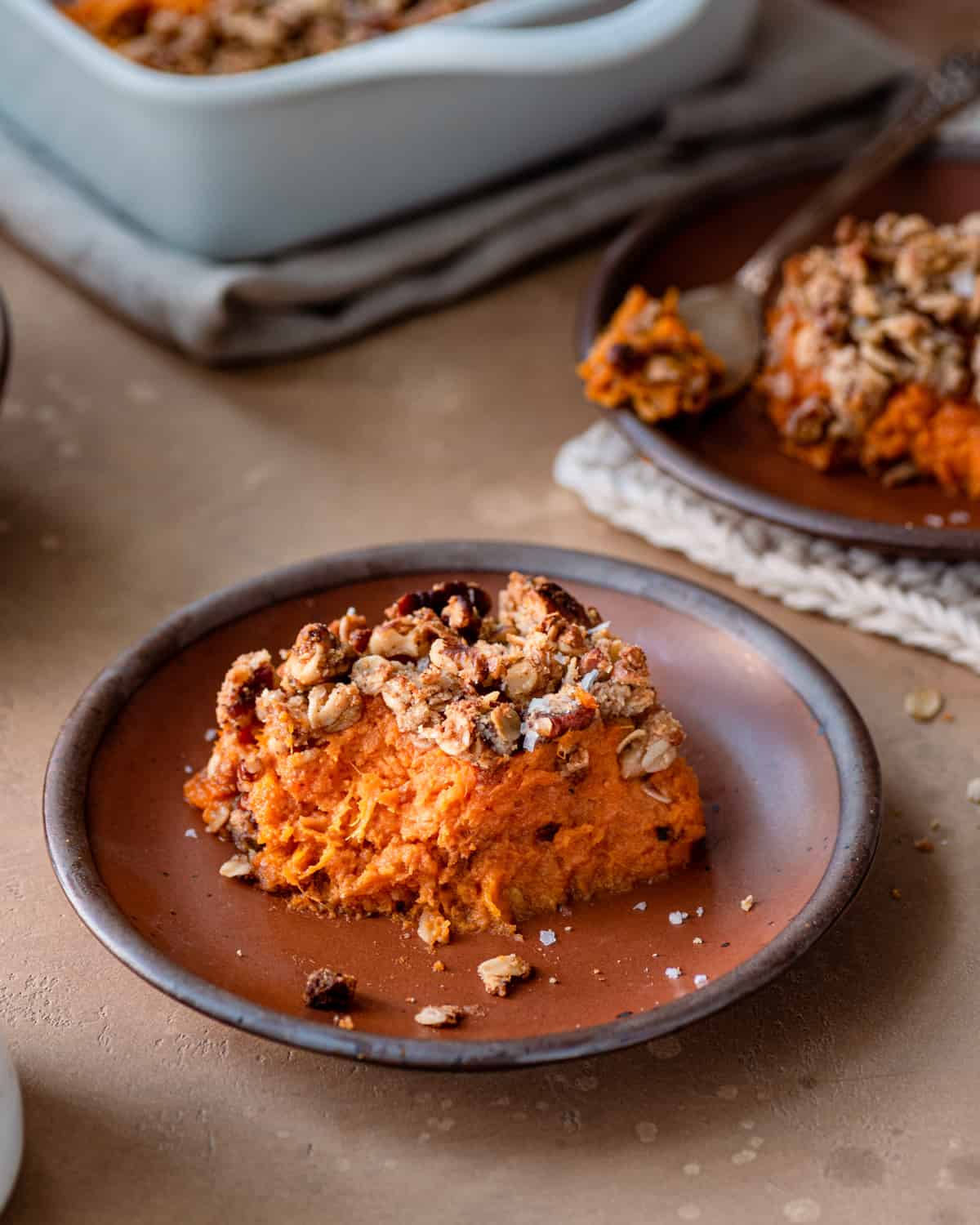 One piece of sweet potato casserole on a brown plate on a table.
