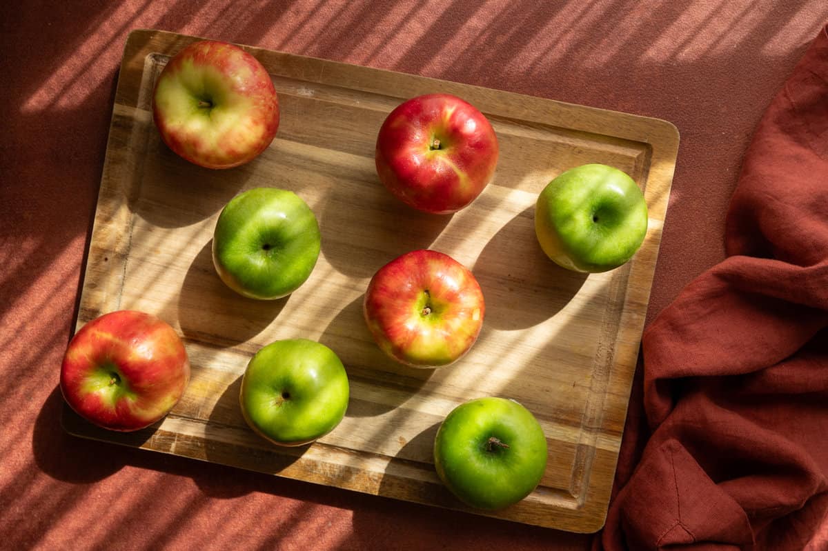 8 apples on a wooden cutting board on a table.