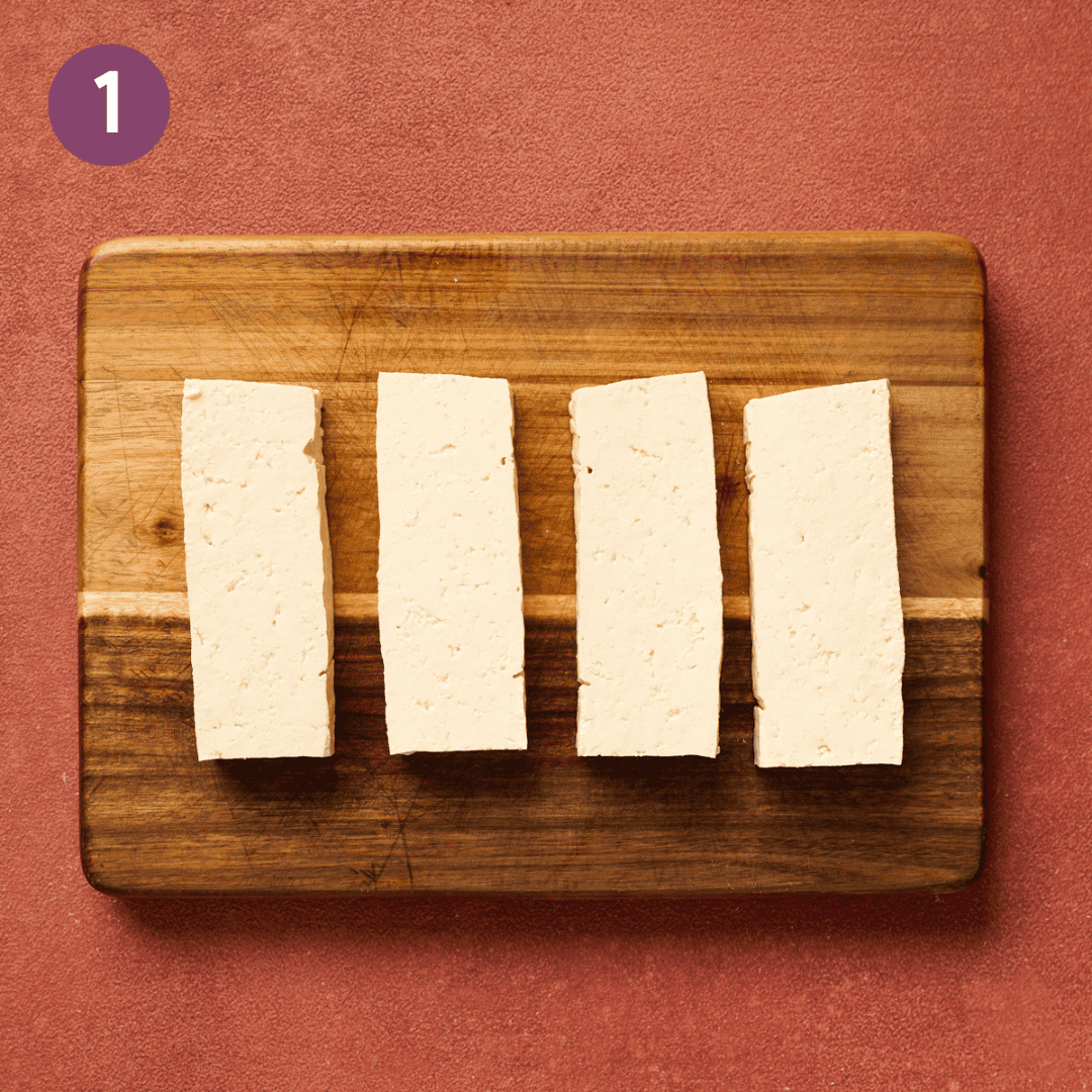 4 tofu slabs on a wooden cutting board.