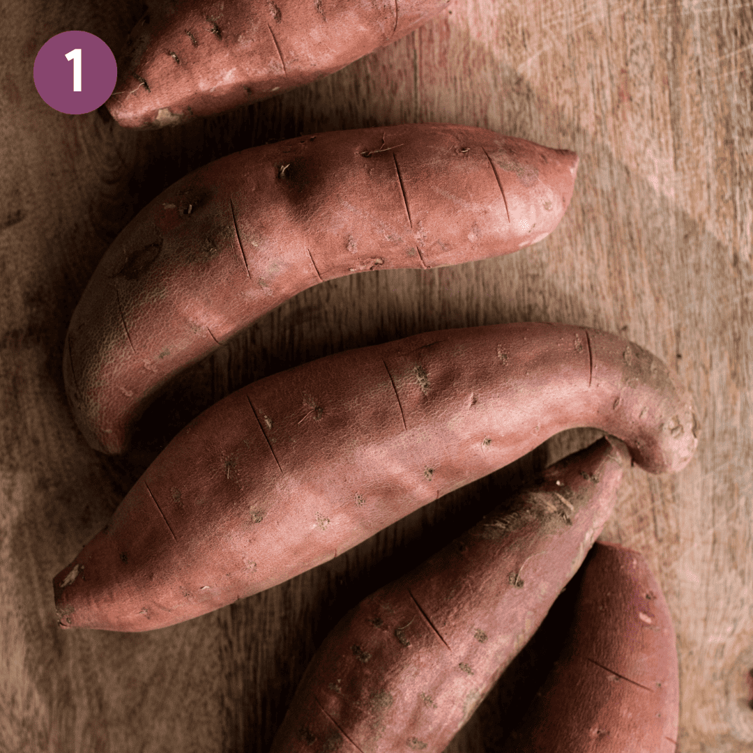 Sweet potatoes on a wooden cutting board.