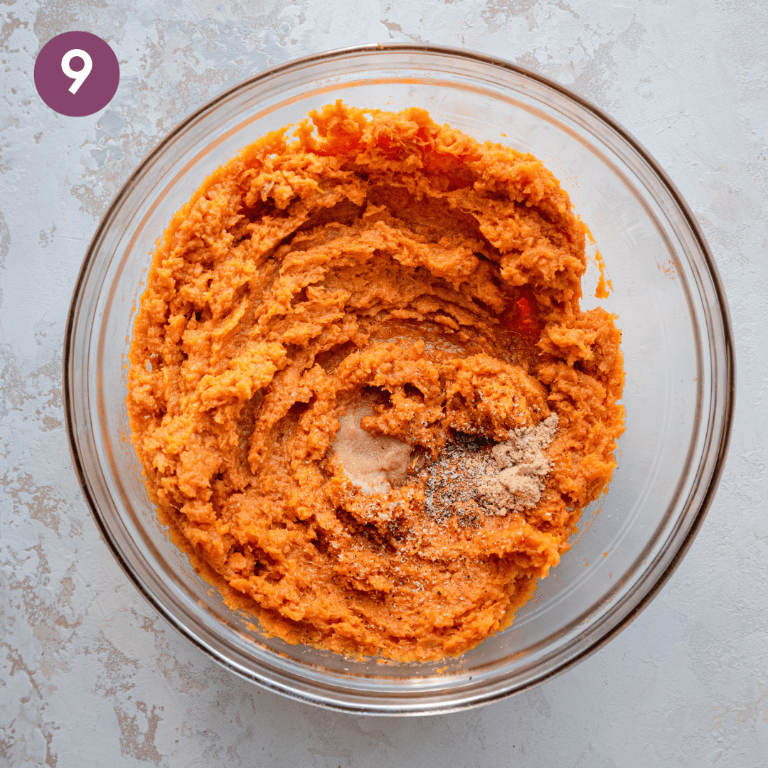 Spices on top of sweet potato mash in a glass bowl.