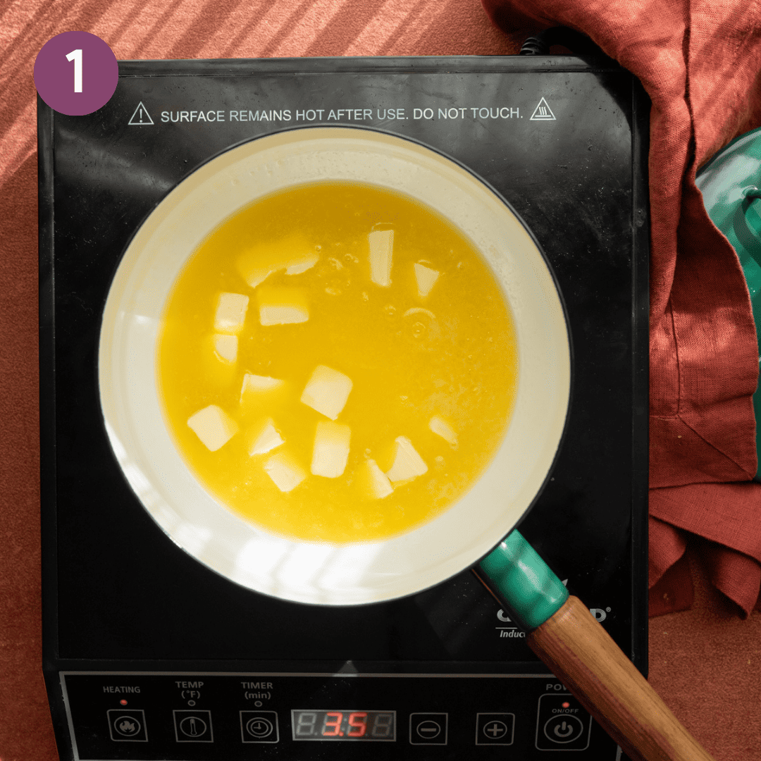 Butter melting in a white saucepan on a portable burner.